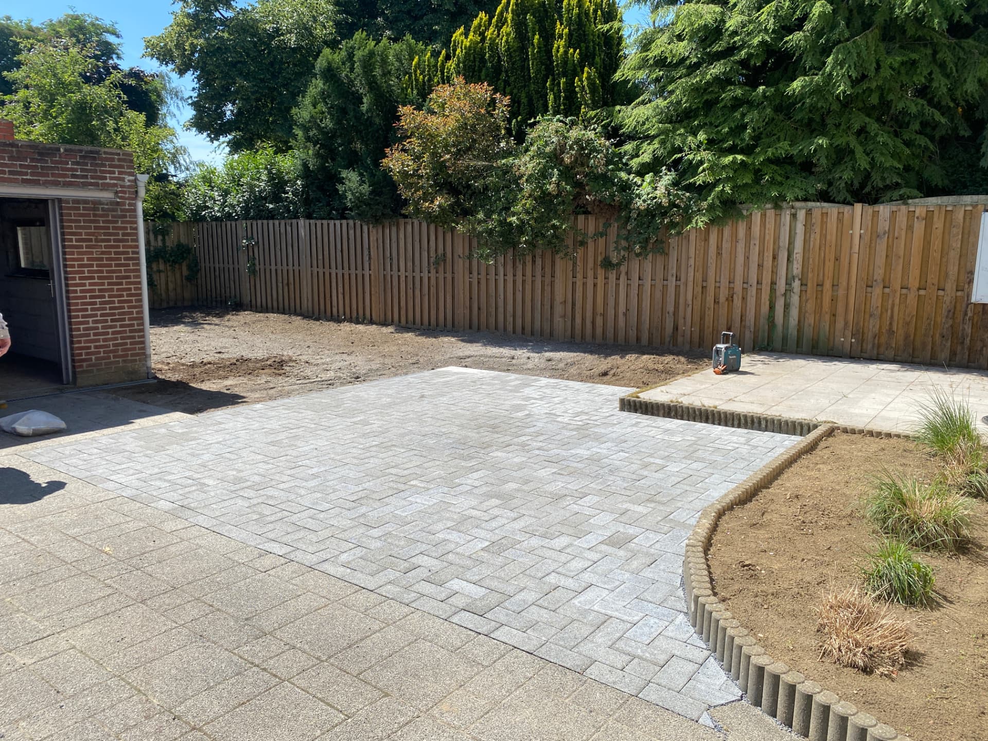 Aangelegde terras met grijze klinkers en betonnen palissade-afboording